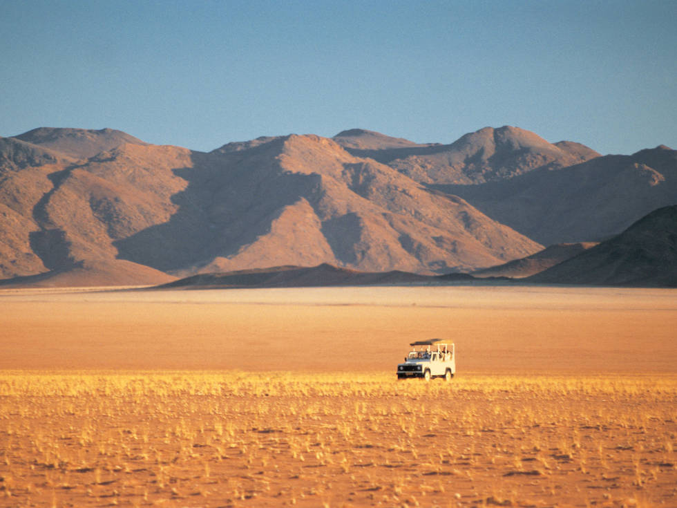Een jeep die rijdt door het Namib Naukluft Park bij Dune Camp. 