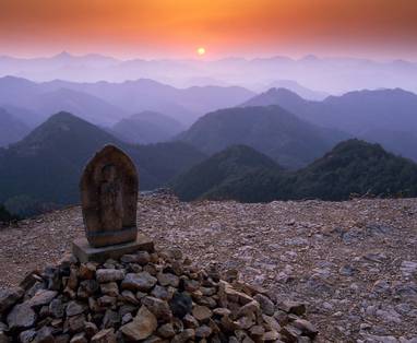 Een grafsteen op een berg met geel blauwe lucht en ondergaande zon in Kyoto. 