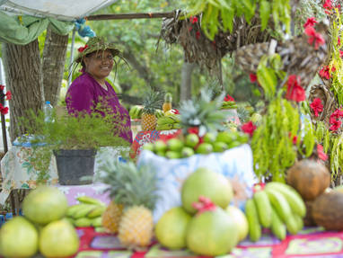 Vrouw achter marktkraam omringd met fruit