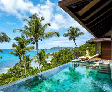 Een infinity pool bij het Six Senses Zyl Payson op de Seychellen met een vrouw en op de achtergrond palmbomen en oceaan. 