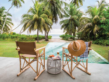 Twee stoelen met uitzicht op een groot zwembad bij de Alphonse Island Logde in de Seychellen. 
