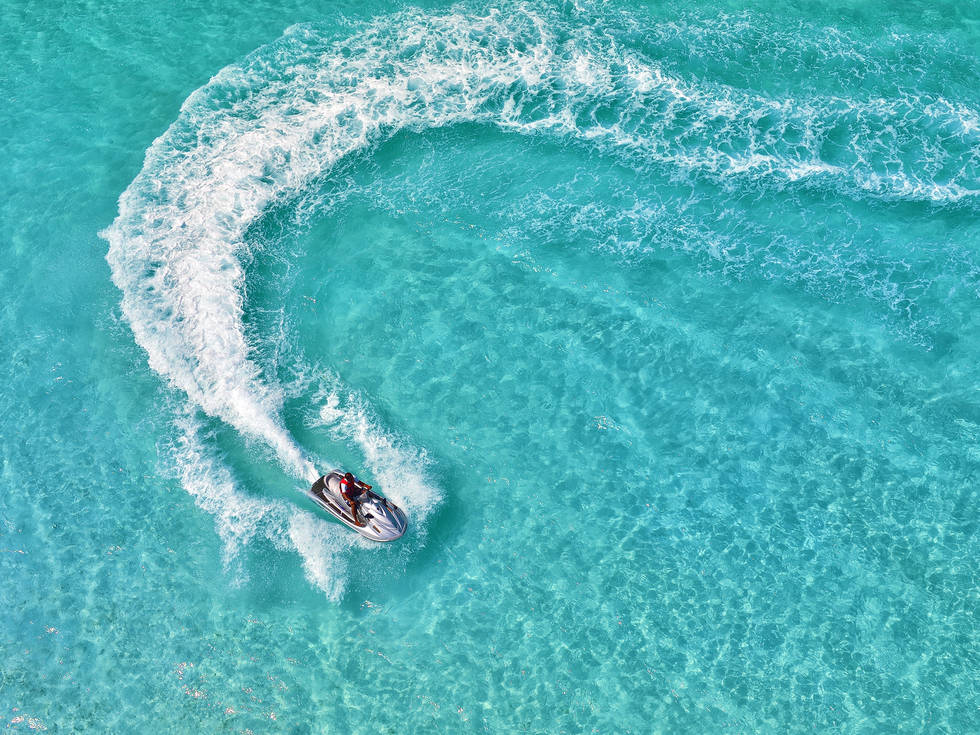Een man die rondjes draait op een jetski in het heldere water van de Malediven.