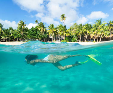 Een snorkelende vrouw bij het Kokomo Private Island Resort op de Fiji eilanden. 