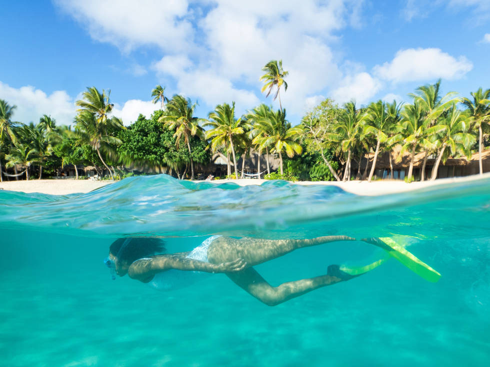 Een snorkelende vrouw bij het Kokomo Private Island Resort op de Fiji eilanden. 