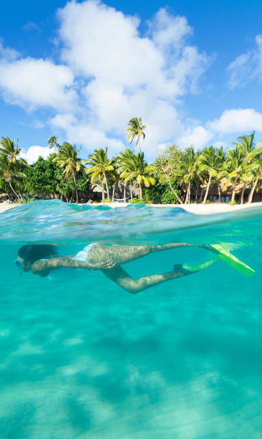 Een snorkelende vrouw bij het Kokomo Private Island Resort op de Fiji eilanden.