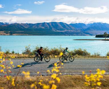 Twee fietsende mensen langs Lake Tekapo in de herfst. 