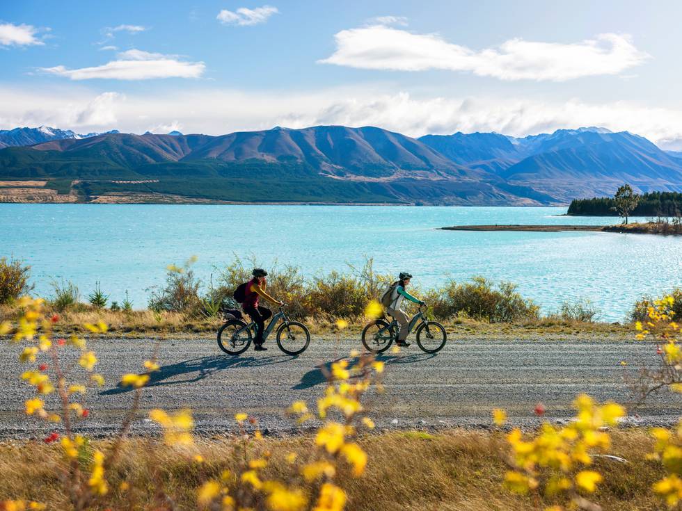 Twee fietsende mensen langs Lake Tekapo in de herfst. 