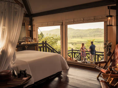 Slaapkamer en mensen die genieten op het terras bij Four Seasons Golden Triangle in Chiang Rai