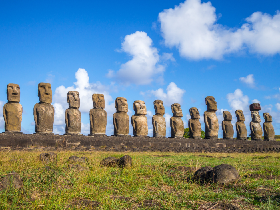 Moai standbeelden op Paaseiland in een rijtje tegen de groene heuvels.