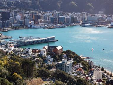 De stad en haven van Wellington aan de zee gelegen en omringd door hoge gebouwen. 