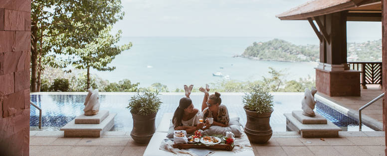 Twee dames bij het pimalai resort in Thailand met als achtergrond een baai met boten en eilanden.
