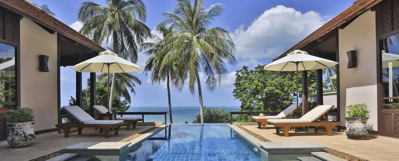 Een villa in het Pimalai Resort met een en uitzicht naar buiten op het zwembad met parasols en ligstoelen.