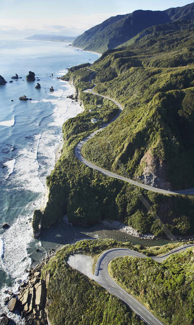 De kust van het Zuidereiland in Nieuw-Zeeland met verschillende berpassen omringd door groene heuvels en ruige oceaan. 
