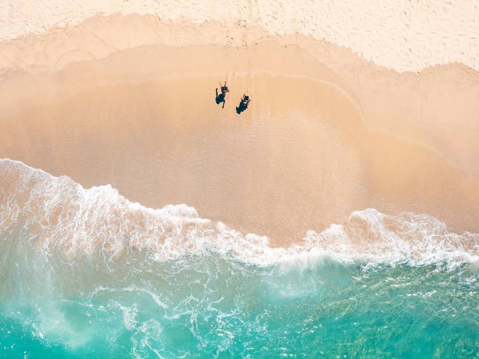 Een luchtfoto van Tamarama Beach met een parasol en twee mensen die op het strand staan.