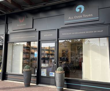 Gevel van het reisbureau met de logo's van ReisGuru en All Over Tours in Roelofarendsveen. 
