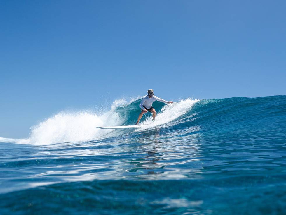 Een surfende man bij de Malediven.