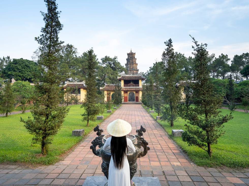 Een Aziatische dame die voor een gebouw staat in de keizerlijke stad Hue in Vietnam