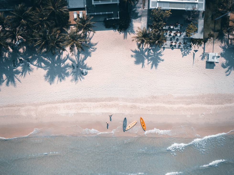 Een foto van bovenaf van het strand in Phu Quoc in Vietnam met boten en palmbomen. 