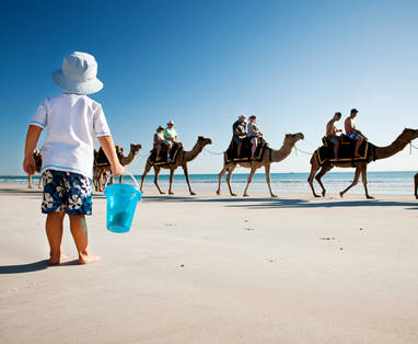 Kamelen en kind op het strand van Broome