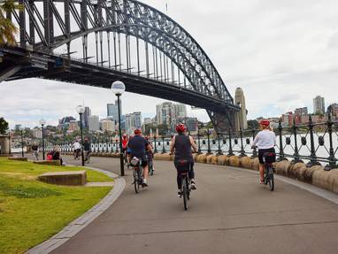 mensen fietsen onder de harbour bridge sydney