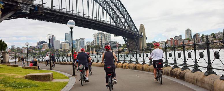 mensen fietsen onder de harbour bridge sydney