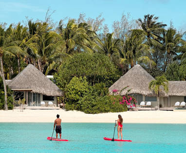 Twee personen staand op paddle bord op blauwe lagune 